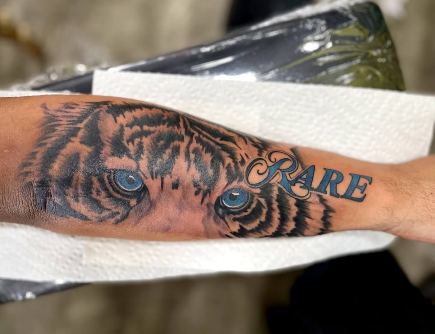 Tiger photo-realism animal tattoo with blue lettering by Lyric at Iron Palm Tattoos in Downtown Atlanta. Call 404-973-7828 . Walk-Ins welcome.