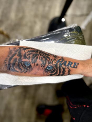 Tiger photo-realism animal tattoo with blue lettering by Lyric at Iron Palm Tattoos in Downtown Atlanta. Call 404-973-7828 . Walk-Ins welcome.