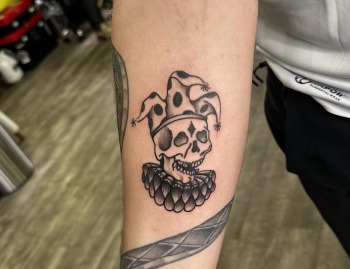 Jester Skull Tattoo By Choze, an artist at Iron Palm Tattoos In Downtown Atlanta GA. The jester skull tattoo can be seen as a reminder of the fragility of life and the inevitability of death. It can also represent the duality of life and death, joy, sorrow, comedy, and tragedy. It can also be a symbol of irony reminding us that even those who bring joy and laughter can experience the same fate as anyone else. Call 404-973-7828 or visit for a free consultation with a body artist. Walk Ins are welcome.