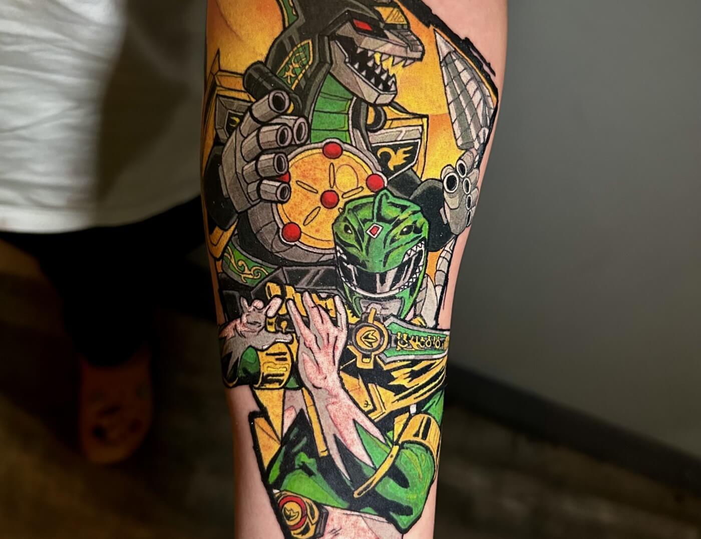 Green Power Ranger & Dragonzord Anime Tattoo In Tribute to the late Jason David Frank by Lyric TheArtist at Iron Palm Tattoos in Atlanta. Jason is best remembered for his role as the green power ranger and had lead roles in all of the Power Ranger's television series. He was also a well known martial artist.We're open late night til 2AM most nights. Stop by for a free consultation with Lyric or another Iron Palm body artist. Call 404-973-7828 or stop by for a free consultation. Walk ins are welcome.