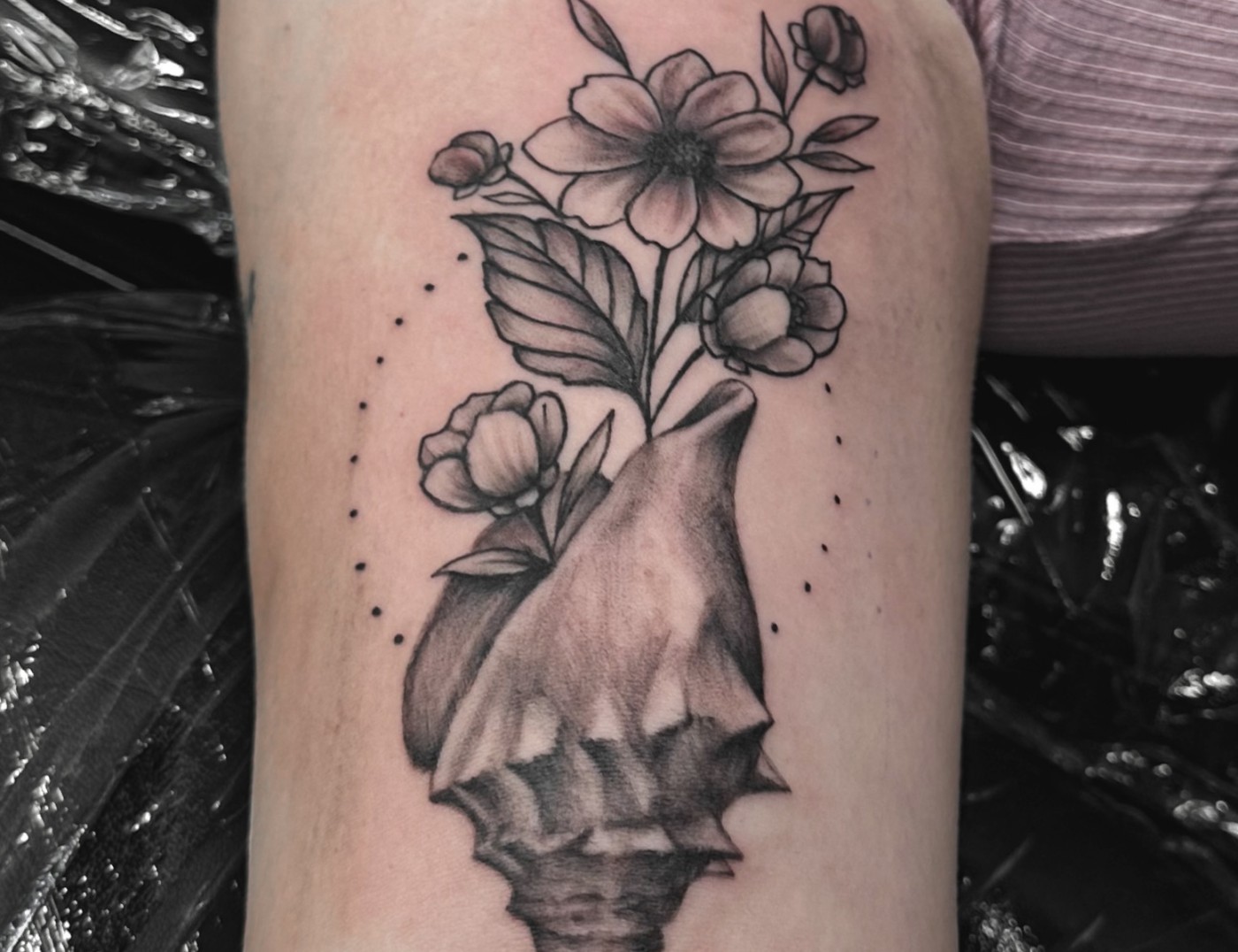 Conch Seashell With Flowers in Bloom Blackwork Tattoo By Choze at Iron Palm Tattoos in downtown Atlanta, Georgia. Conch shells symbolize fertility as the flowers and plant life on this tattoo depict. Our most senior artist, Choze specializes in fine line blackwork tattoos but has mastered many other styles. We're Atlanta's only late night tattoo shop. Call 404-973-7828 or stop by for a free consultation. Walk Ins are welcome.