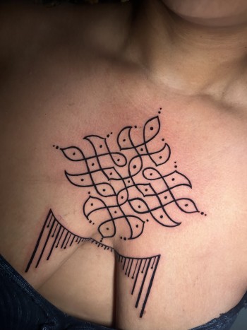 Fine Line Kolam Tattoo in Black Ink by Lyric the Artist At Iron Palm Tattoos In Atlanta., Kolam, also known as rangoli, is a traditional form of decorative art that is practiced in Southern Asia and more specifically, Sothern India. It involves creating intricate and colorful geometric patterns. These patterns are typically geometric or nature-inspired and are created as a form of decoration, often during festivals, special occasions, or daily rituals. The intricate and visually appealing nature of Kolam patterns have symbolism far beyond the original cultural beliefs such as luck, prosperity, unity, and spirituality. We're open late night until 2AM most nights. Call 404-973-7828 or stop by for a free consultation. Walk ins are welcome.
