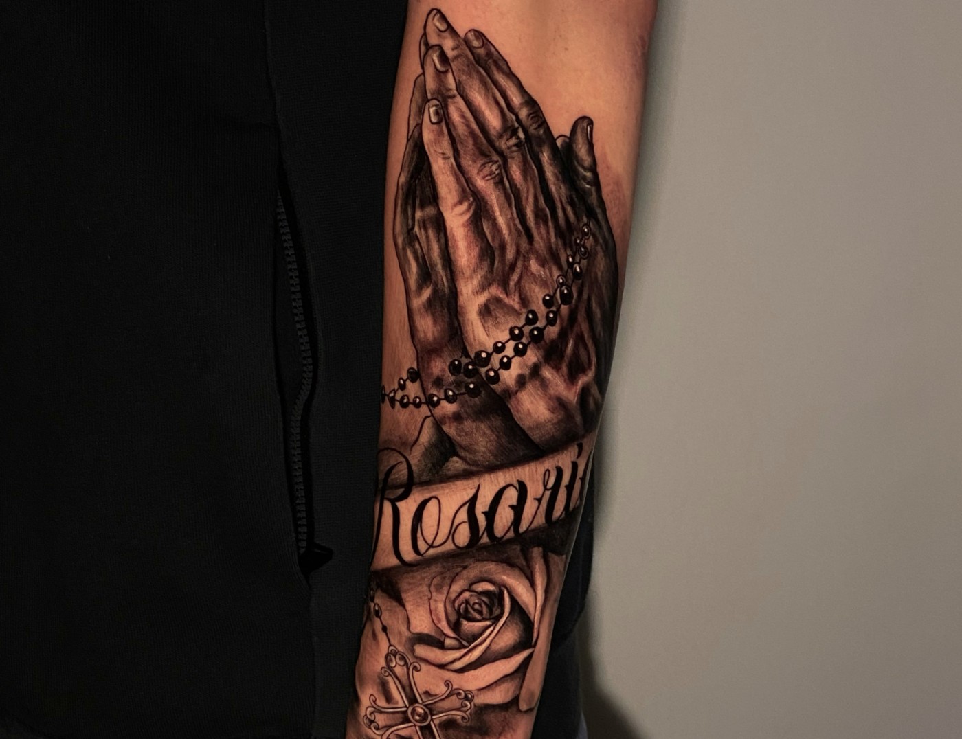 "Rosario" Script Lettering Tattoo With Photo Realism Praying Hands By Rene Cristobal at Iron Palm Tattoos in downtown Atlanta, Georgia. Rene is a resident artist at Iron Palm and comes to us from Vision Tattoo Studio in Concepcion, Chile. Call 404-973-7828 or stop by for a free consultation. Walk ins are welcome.