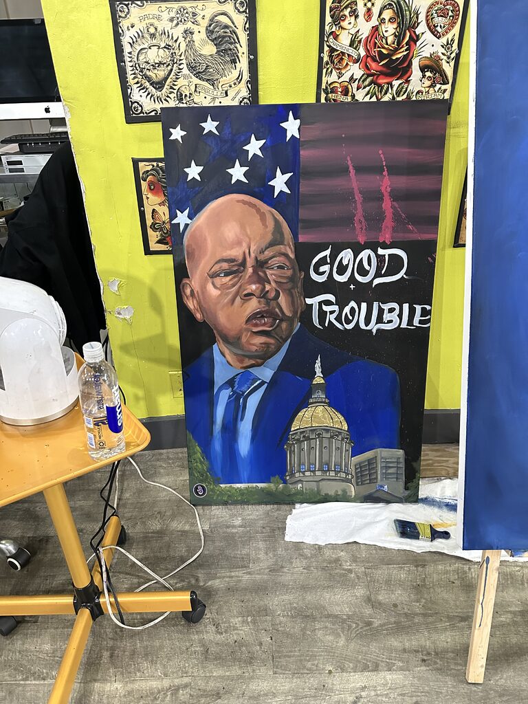 00 USD - "Uncle J: 'Good Trouble'" Painting By Marlon Blake at Iron Palm Tattoos. Marlon painted this inspiration as a tribute to the late senator John Lewis. Senator Lewis was instrumental in bringing about change during the civil rights movement. One of Dr King's proteges he went on to serve his people, state, and country until he passed away in office.. This piece is 00.00 and can be purchased online only on IronPalmTattoos.com.