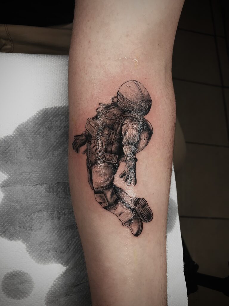Astronaut Blackwork Tattoo By Rene Cristobal At Iron Palm Tattoos. We love how the astronaut is floating free on his arm. Call 404-973-7828 or stop by for a free consultation. Open til 2AM. Walk-ins are welcome.