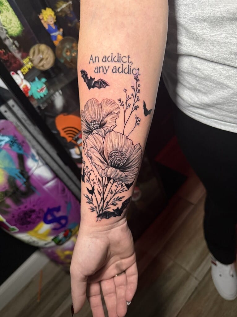 Black and gray floral forearm tattoo with quote and bats design