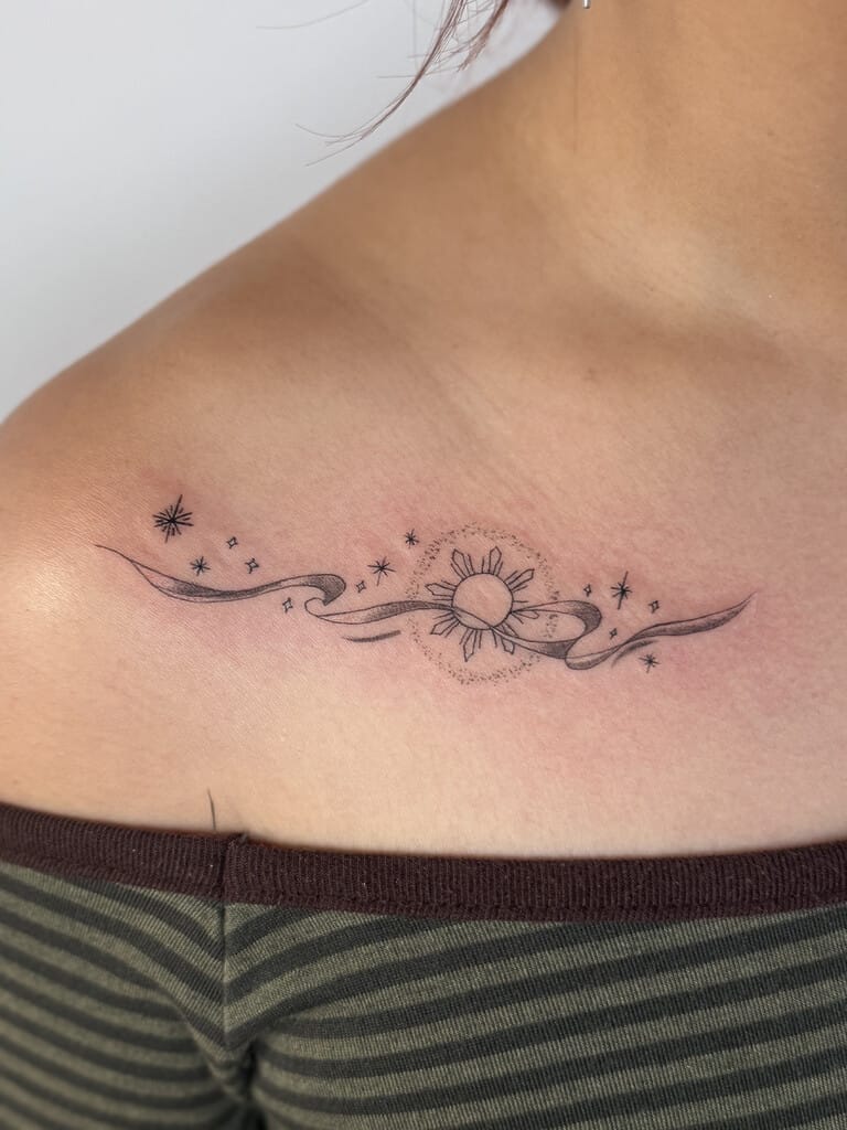Fine line sun and stars tattoo across collarbone with flowing ribbon design and soft shading