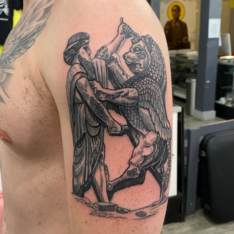 A detailed Blackwork tattoo depicting a mythological battle between a warrior and a winged creature, built with bold outlines, fine hatching, and engraving-inspired shading. Tattooed by Tupicalo at Iron Palm Tattoos & Body Piercings in downtown Atlanta, GA. Call or text 404-973-7828. Tattoo consultations are free and walk ins are always welcome.